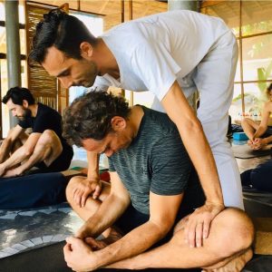 Yoga teacher trainer assisting student